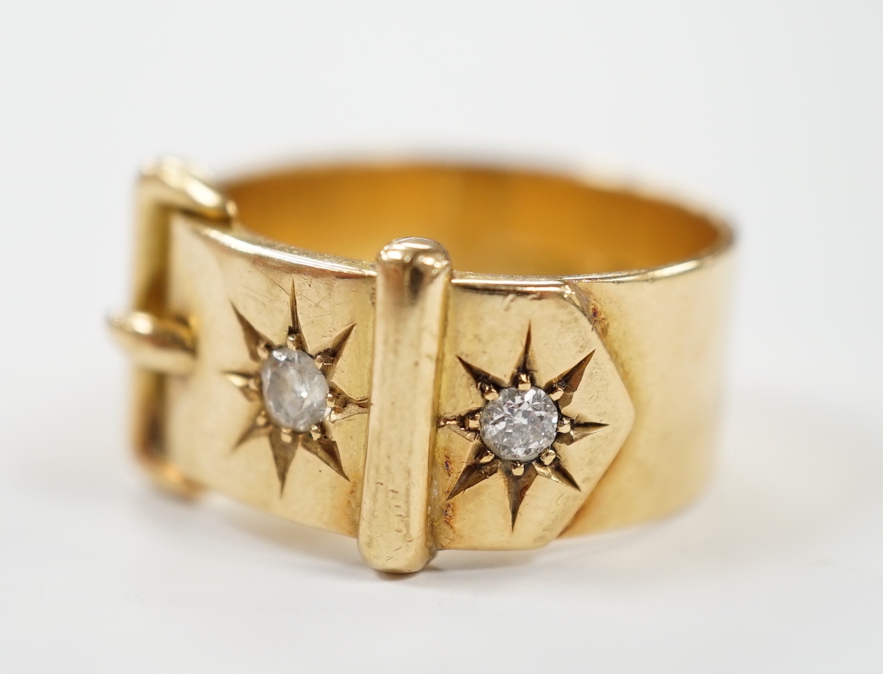 A George V 18ct gold and two stone diamond set buckle ring, size T, gross weight 11.9 grams.